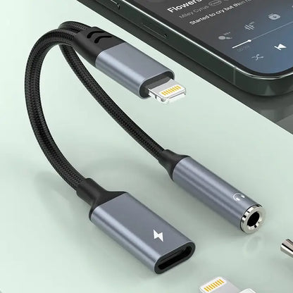 A black braided audio adapter cable with a USB-C to Lightning connector on one end and a 3.5mm headphone jack on the other, shown next to a smartphone on a light mint background.
